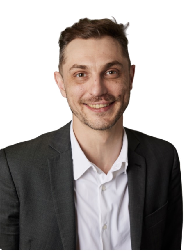Studio portrait of Grant Blaisdell in a dark blazer and white shirt