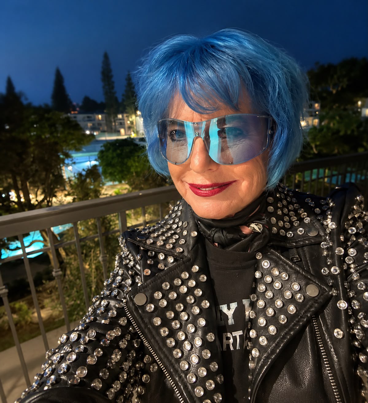Eva Blaisdell at night in a studded black leather jacket, blue hair and dark glasses